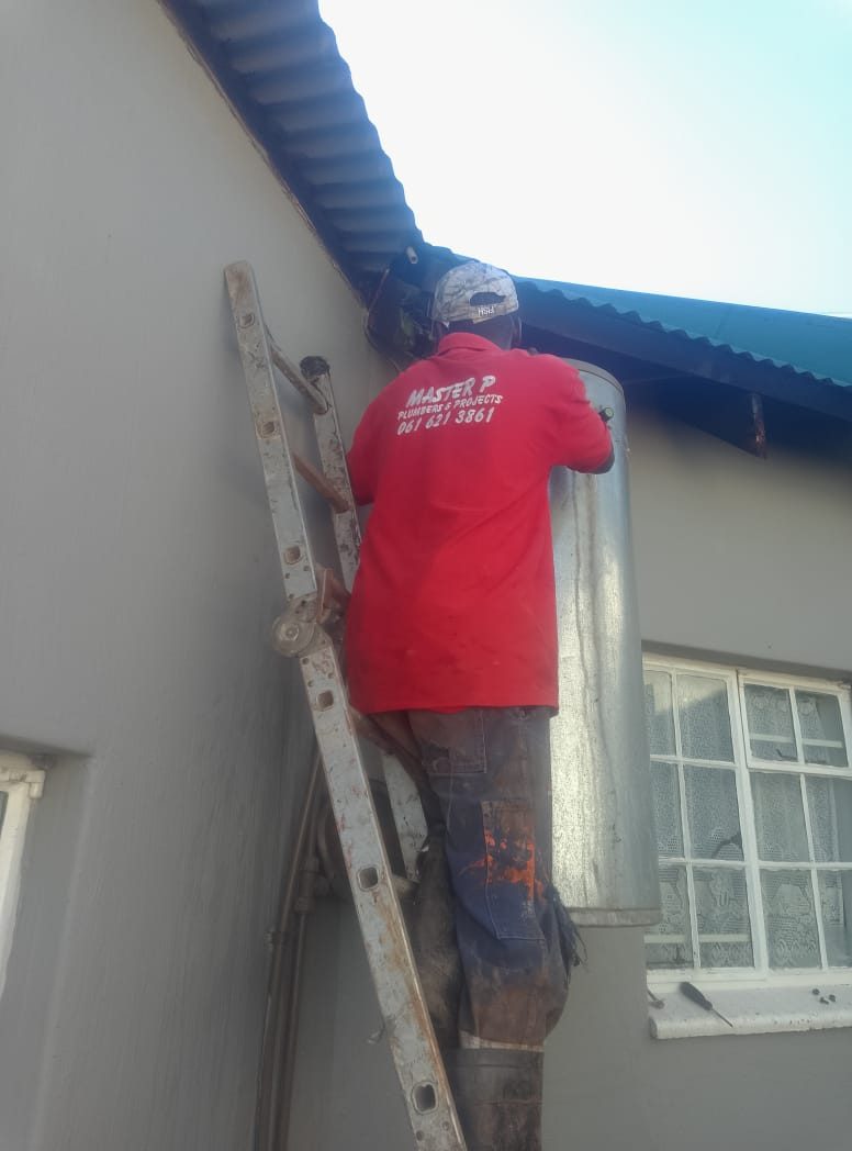 Plumber installing an electric geyser on an exterior wall